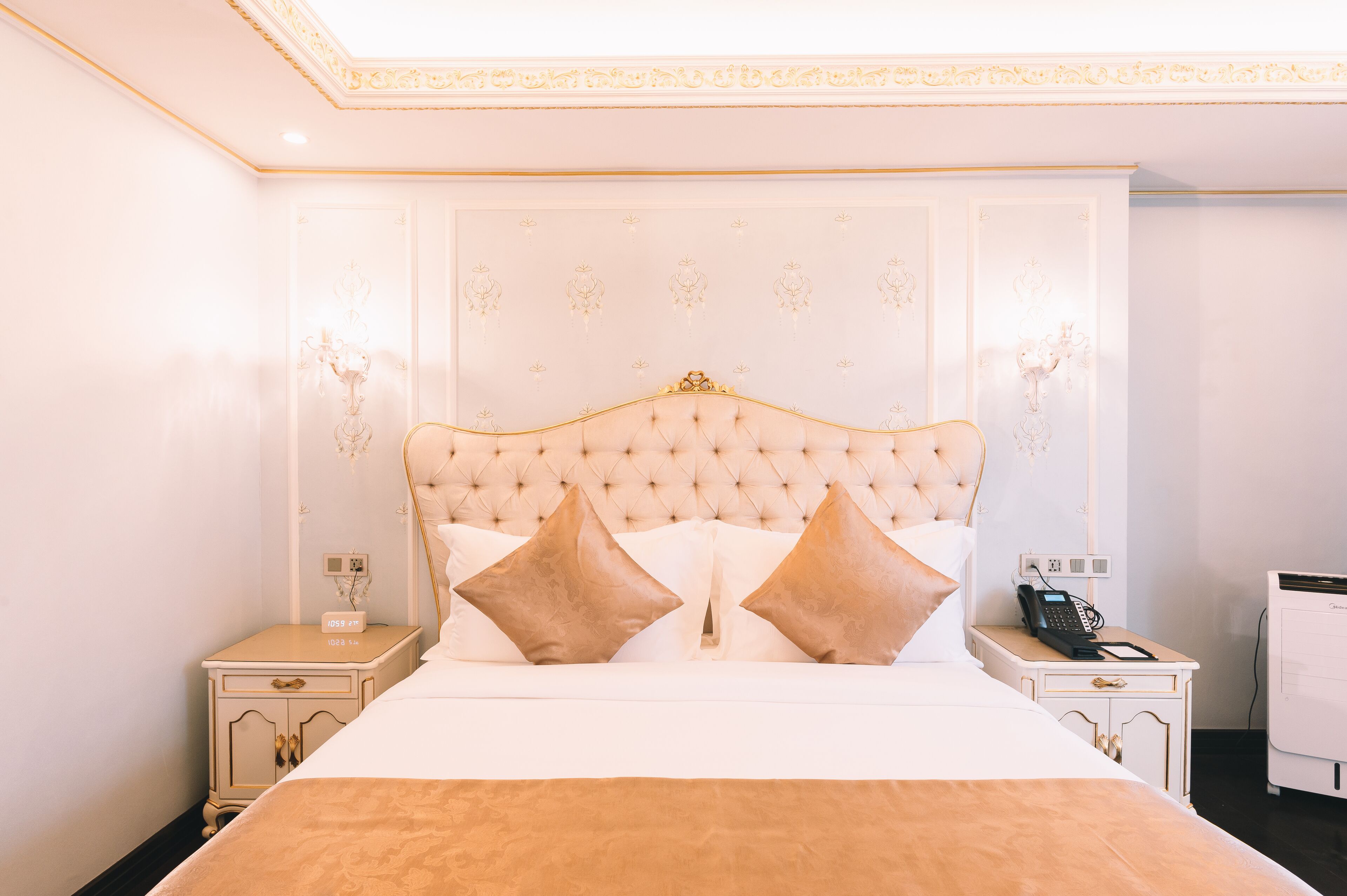 Ein Hotelzimmer mit einem großen Bett, zwei Nachttischen, einem Beistelltisch und einem an der Wand montierten Telefon.