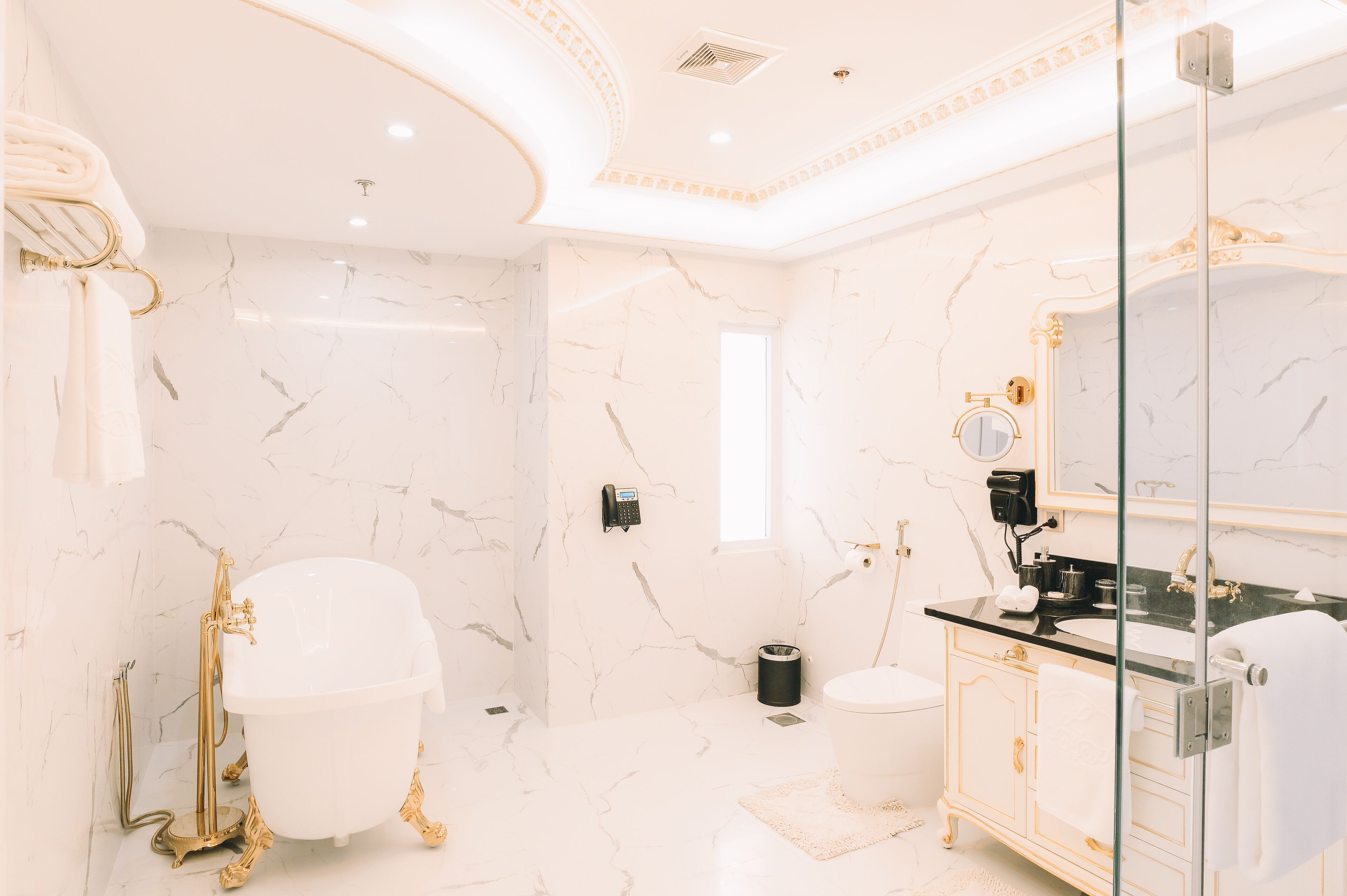 A luxurious bathroom with a clawfoot bathtub, a glass-enclosed shower, and a classic vanity with gold fixtures.