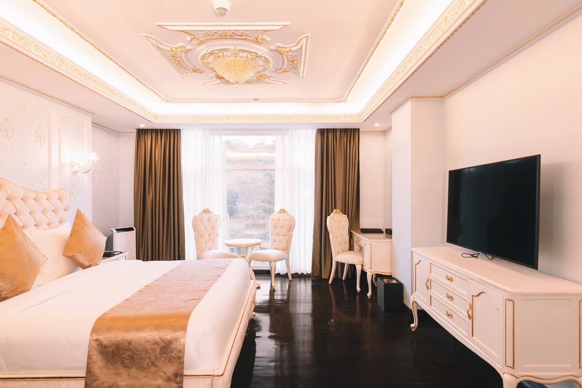 Een luxe hotelkamer met een groot bed, een televisie, een bureau en een stoel.