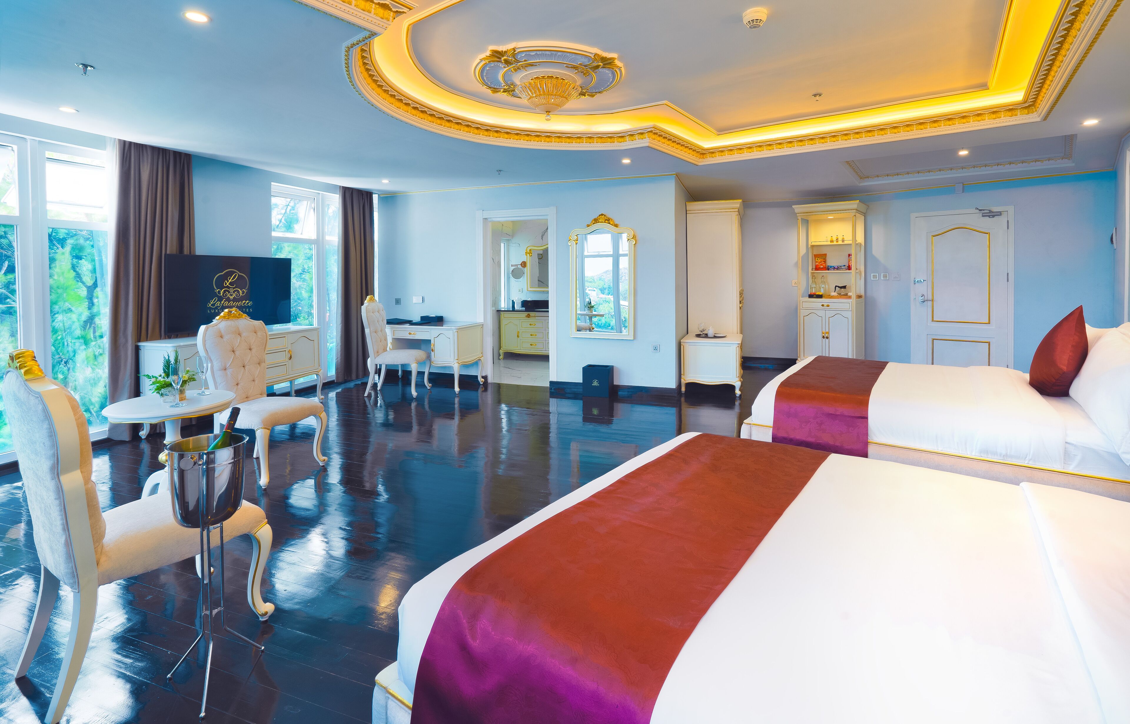A hotel room with two beds, a desk, a chair, and a TV.