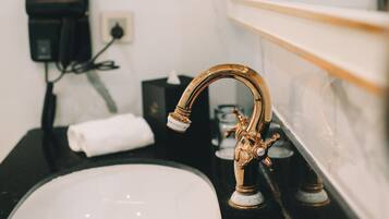 A bathroom with a gold faucet, a white sink, and two round mirrors on the wall.