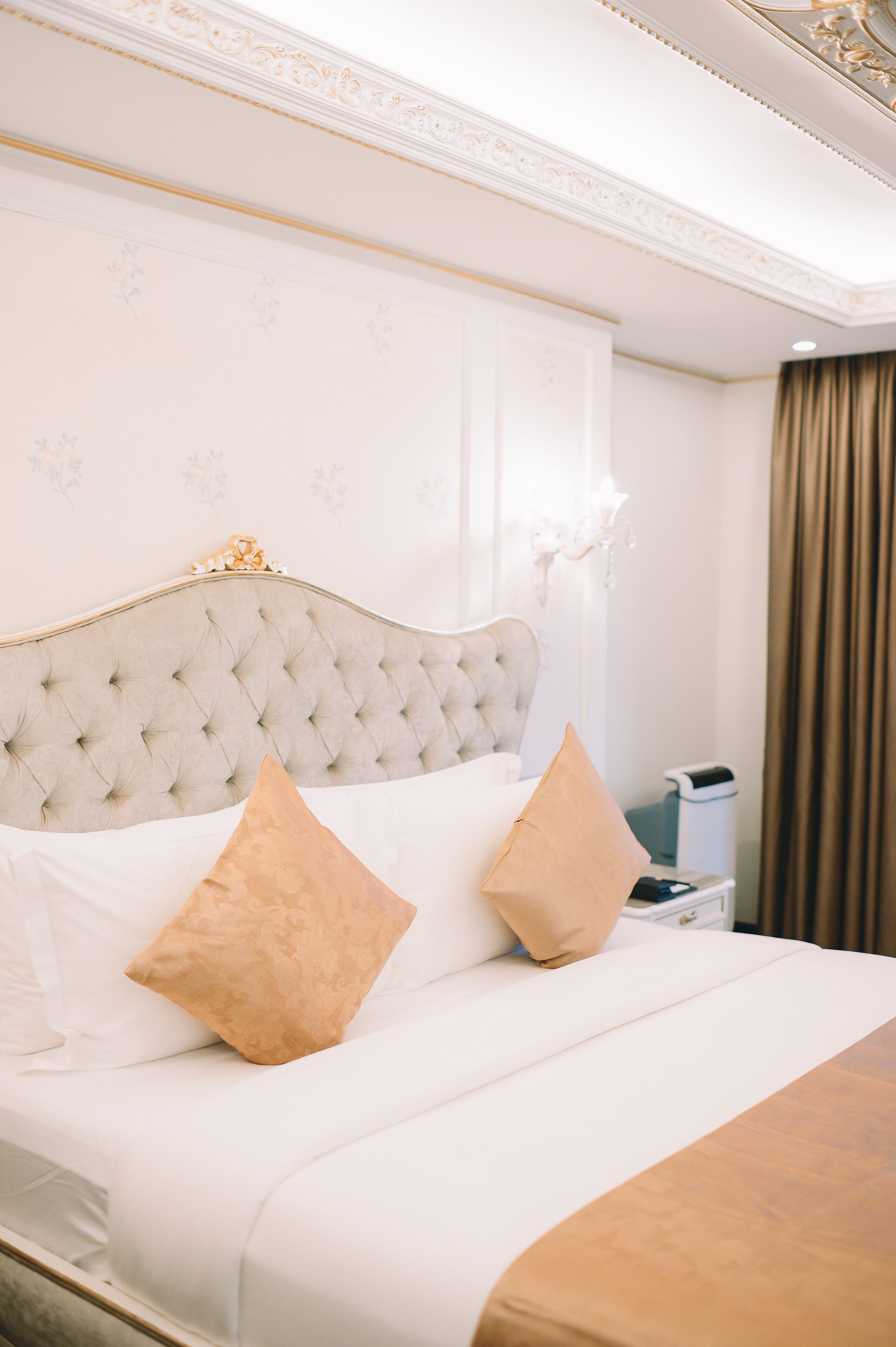A neatly made bed with a tufted headboard, two pillows, and a bedside table with a lamp.