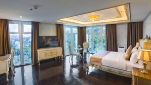 Un dormitorio espacioso con una cama grande, un tocador, una televisión y vistas al exterior.