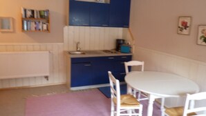 Una cocina compacta con armarios azules, una encimera blanca y una mesa redonda con sillas.