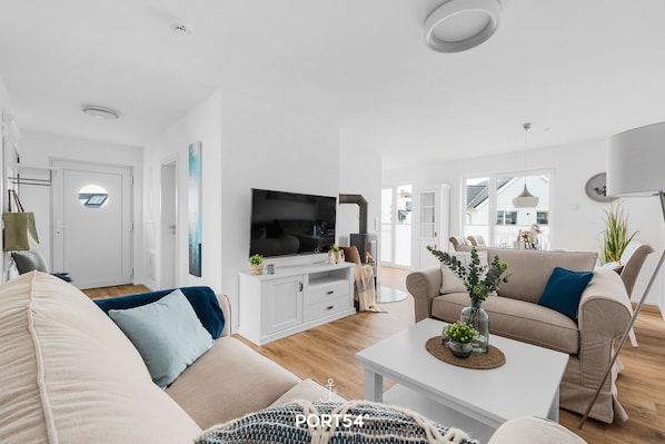 A modern living room with a flat-screen TV, a white entertainment unit, and a beige sofa.