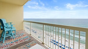 A balcony with a view of the beach, chairs, and a patterned rug. - Renovated 1BR Celadon Condo | Gulf Views, Balcony, Bunks + Beach Chairs Included! (Panama City Beach)