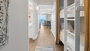 A hotel corridor with bunk beds, a dining area, and a view of the outdoors. - Renovated 1BR Celadon Condo | Gulf Views, Balcony, Bunks + Beach Chairs Included! (Panama City Beach)