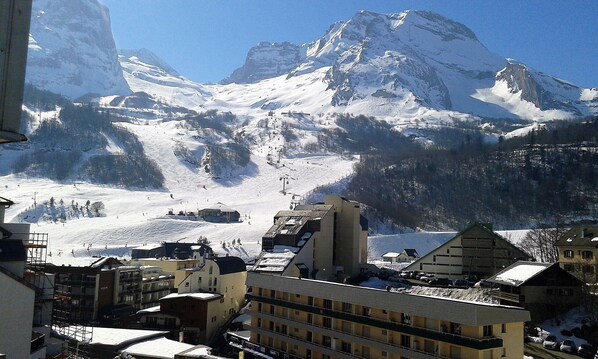 Eine verschneite Berglandschaft mit einem Skigebiet im Hintergrund.