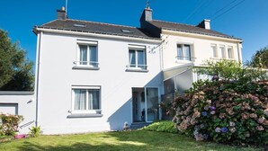 A two-story white house with a balcony, a small garden with hydrangeas, and a clear blue sky. - entre parc et Haras - Hennebont (Hennebont)