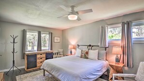 A bedroom with a bed, bedside tables, a chair, a coat rack, and a window with curtains. - Near Beaches and Speedway! Dog-Friendly Hidden Gem (Port Orange)