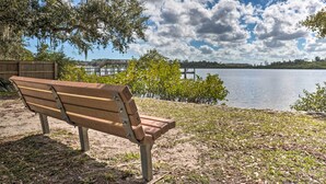 A wooden bench by a lake with a view of a dock and trees. - Near Beaches and Speedway! Dog-Friendly Hidden Gem (Port Orange)