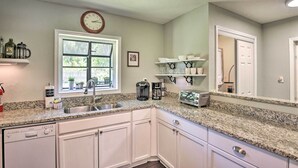 A kitchen with white cabinets, a granite countertop, a coffee maker, and a toaster. - Near Beaches and Speedway! Dog-Friendly Hidden Gem (Port Orange)