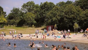 A crowded beach with people swimming and sunbathing, a small structure, and dense trees in the background. - Luxury Villa in France with Private Pool (Les Forges)