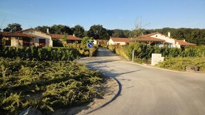 A rural road with houses on either side, a blue directional sign, and a clear sky. - Luxury Villa in France with Private Pool (Les Forges)