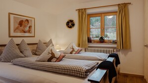 Een slaapkamer met een bed, geruit beddengoed, een ingelijst beeld, een raam met gordijnen en een radiator.