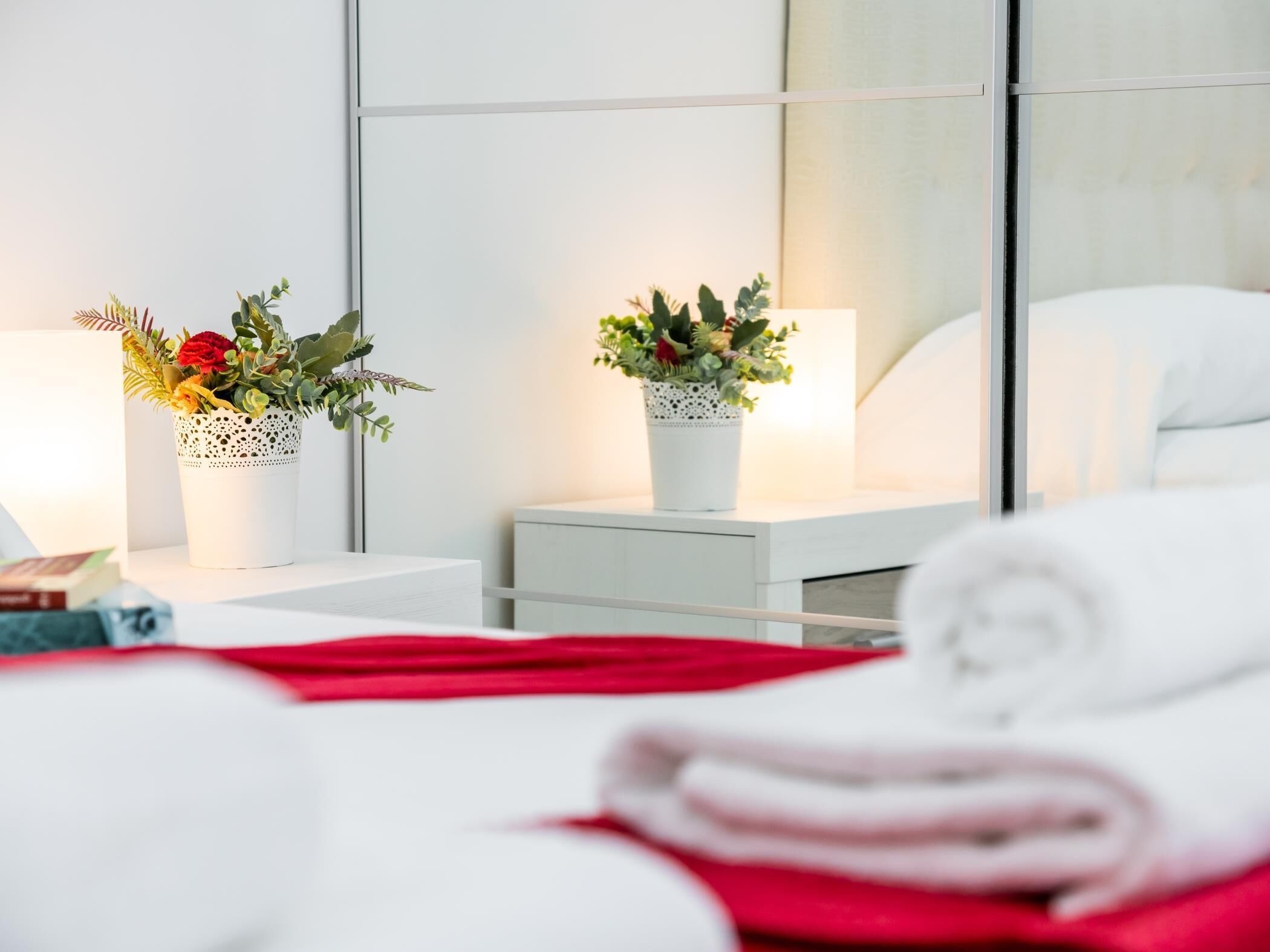 Une chambre d’hôtel avec un lit bien fait, deux tables de chevet avec des lampes et deux plantes en pot.