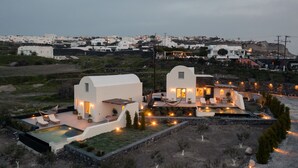 A modern villa with a swimming pool, outdoor seating, and a view of the surrounding landscape.