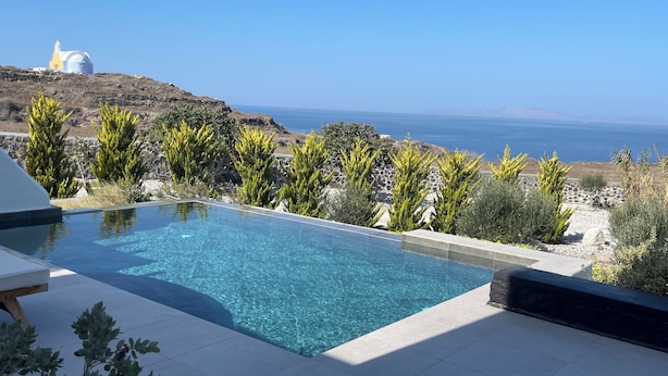 A swimming pool with a view of the sea and a church on a hill.