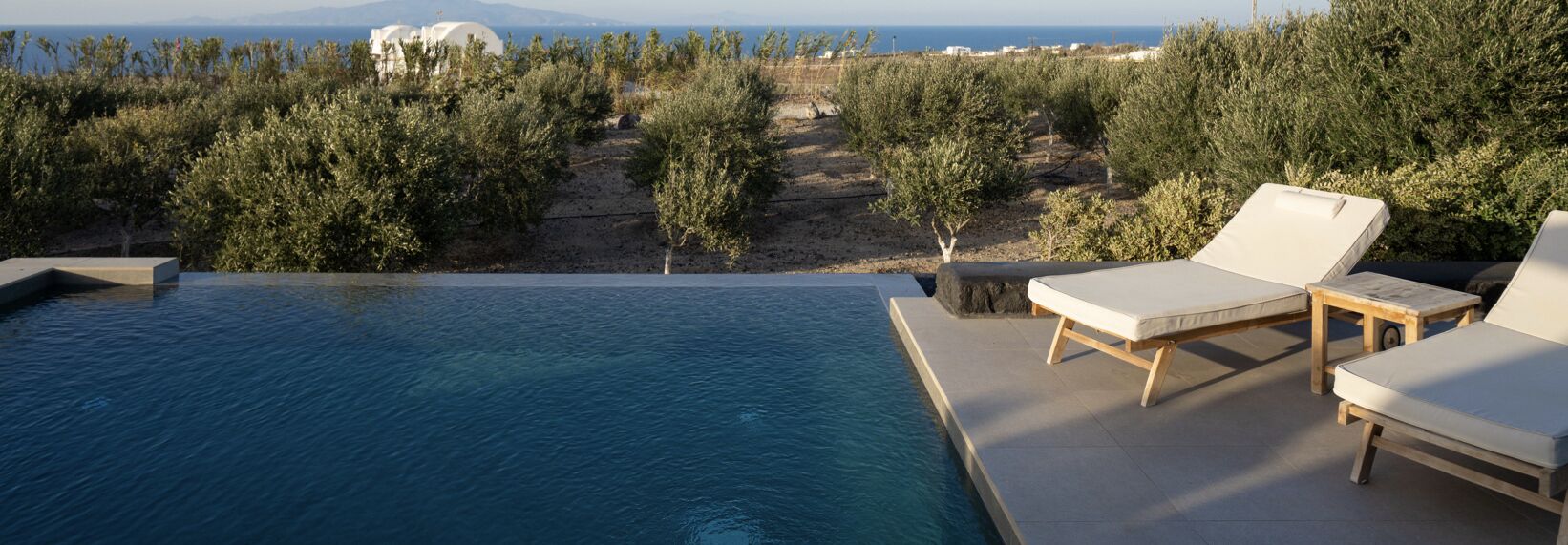 Et evighedsbassin med liggestole og udsigt over havet og landskabet.