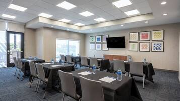 A conference room with tables, chairs, water bottles, and framed artwork on the wall.