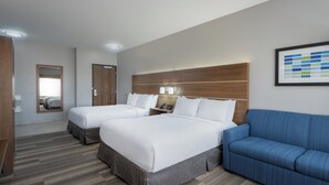 A hotel room with two beds, a blue sofa, a wooden headboard, and a framed picture on the wall.