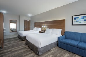 A hotel room with two beds, a blue sofa, a wooden headboard, and a framed picture on the wall. - Holiday Inn Express & Suites Gilbert Mesa Gateway Airport by IHG (Gilbert)