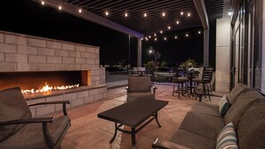 An outdoor patio area with a fire feature, seating, and string lights.