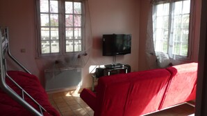 Ein Zimmer mit einem Bett, einem Fernseher und einem fensterbepflanzten Fenster.