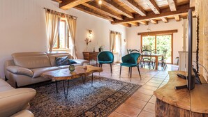 Una sala de estar con un sofá, sillas, una mesa de centro, un televisor y un comedor con una mesa y sillas.