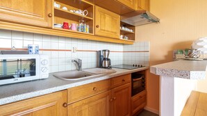 A compact kitchen with wooden cabinets, a microwave, a coffee maker, and a small oven. - T2 Apartment Biscarrosse - AC, Parking, 4 guests, City Center (Biscarrosse Plage)