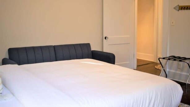A bedroom with a bed, a chair, and a door.