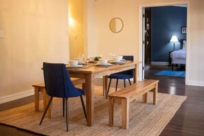 A dining area with a wooden table set for four, two blue chairs, and a bench. - Mins to ASU & Downtown- Foxy on Felder (Montgomery)