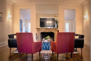 A room with a fireplace, a television mounted above it, and two red armchairs facing the fireplace. - Mins to ASU & Downtown- Foxy on Felder (Montgomery)