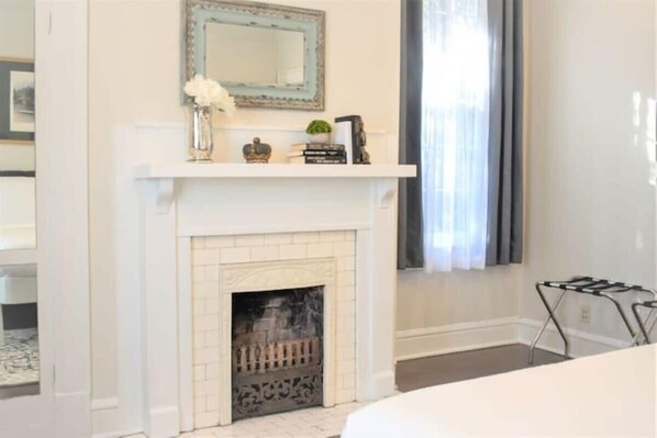 A room with a white fireplace, a mirror above it, and a shelf with decorative items.
