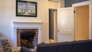 A living room with a fireplace, a patterned armchair, and a sofa.