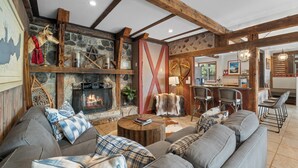 Ein gemütliches Wohnzimmer mit Kamin aus Stein, Holzbalken und einem großen Ecksofa.