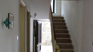 Eine Treppe führt zu einer zweiten Etage, ein Flur mit einer Tür und einer Wandleuchte.