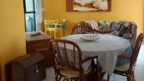 A dining area with a round table, chairs, a sofa, and a painting on the wall. - Dune& Ocean Views Paradise 2 Beds in Natal (Natal)