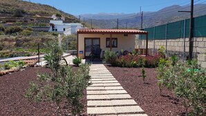 Ein kleines Gebäude mit einem Ziegeldach, umgeben von einem Garten mit einem Kiesweg zum Eingang.