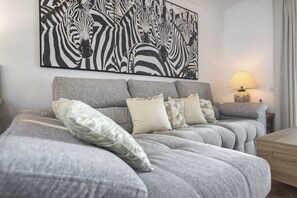 A modern bedroom with a grey sofa bed, a large abstract zebra artwork, and a bedside lamp. - Playa Canela I - Punta del Moral Beach PPHC36P36 (Punta del Moral)