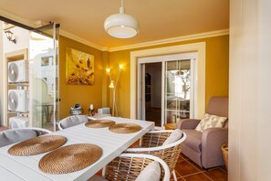 Un espace repas comprenant une table, des chaises et donnant sur l’extérieur.