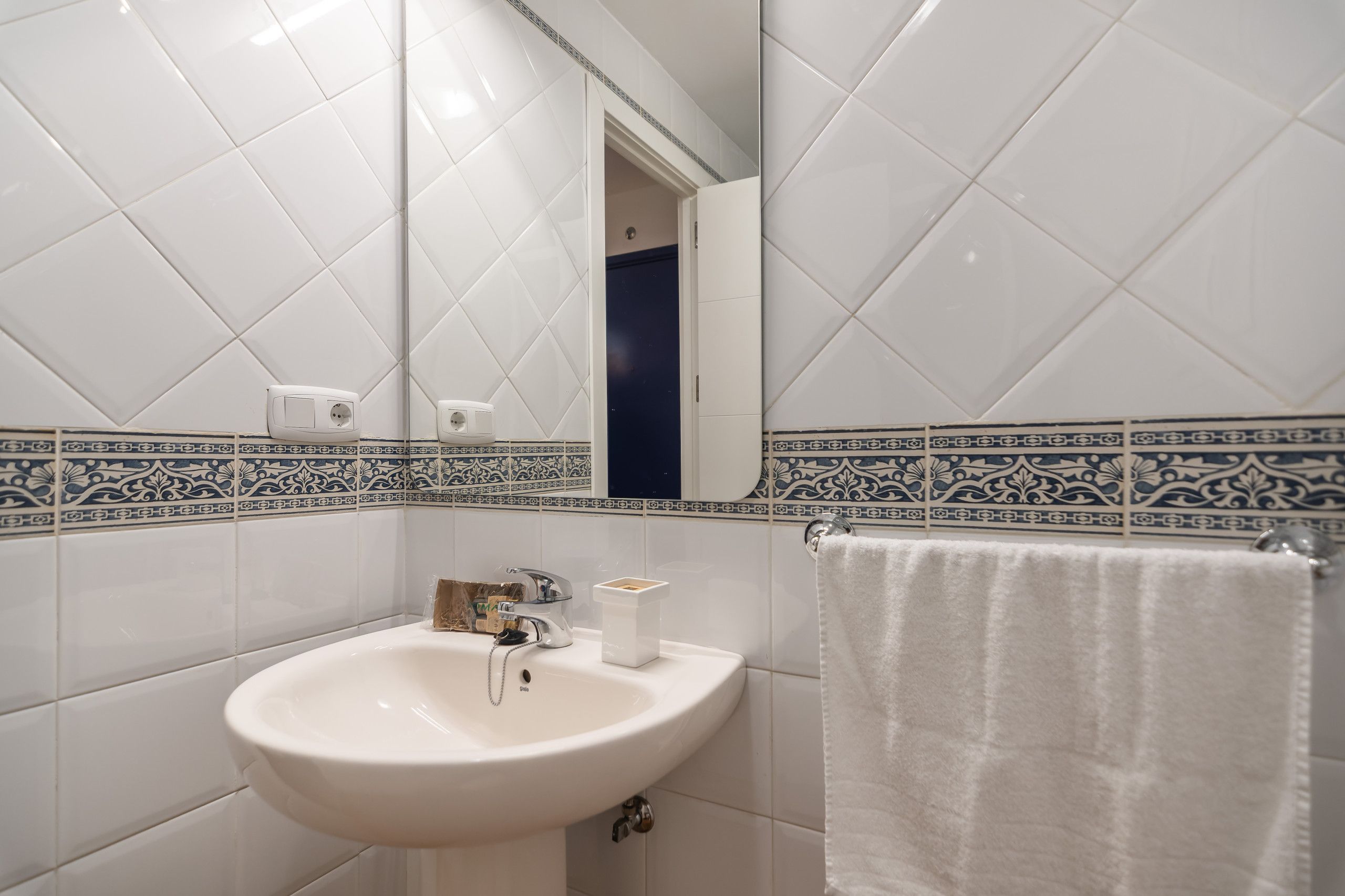 A bathroom with a white sink, a mirror, and a towel rack.