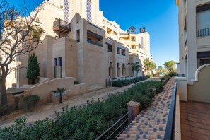 A multi-story building with balconies, a paved pathway, and greenery. - Playa Canela I - Punta del Moral Beach PPHC36P36 (Punta del Moral)