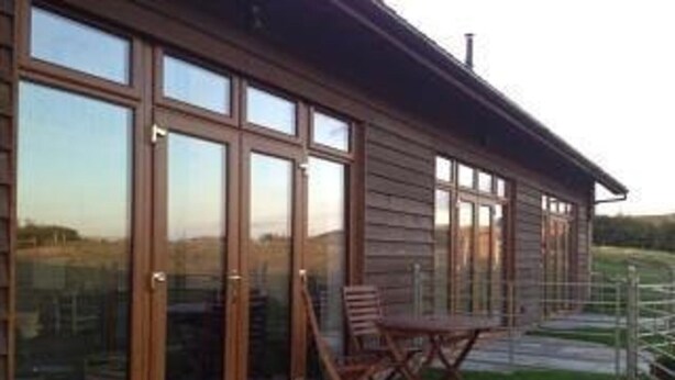 A long, wooden building with large glass windows and a patio area with a chair. - Surf Shack, 1-bed Cottage, Sleeps 2, Pet Friendly (Newport)