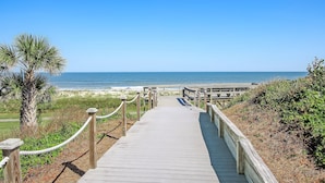 A wooden boardwalk leading to a beach with a clear view of the ocean. - Renovated Oceanfront Condo with Ground-Level Patio on Amelia Island (Fernandina Beach)