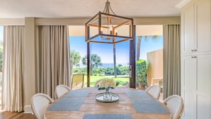 A dining area with a wooden table, woven chairs, and a central chandelier. - Renovated Oceanfront Condo with Ground-Level Patio on Amelia Island (Fernandina Beach)