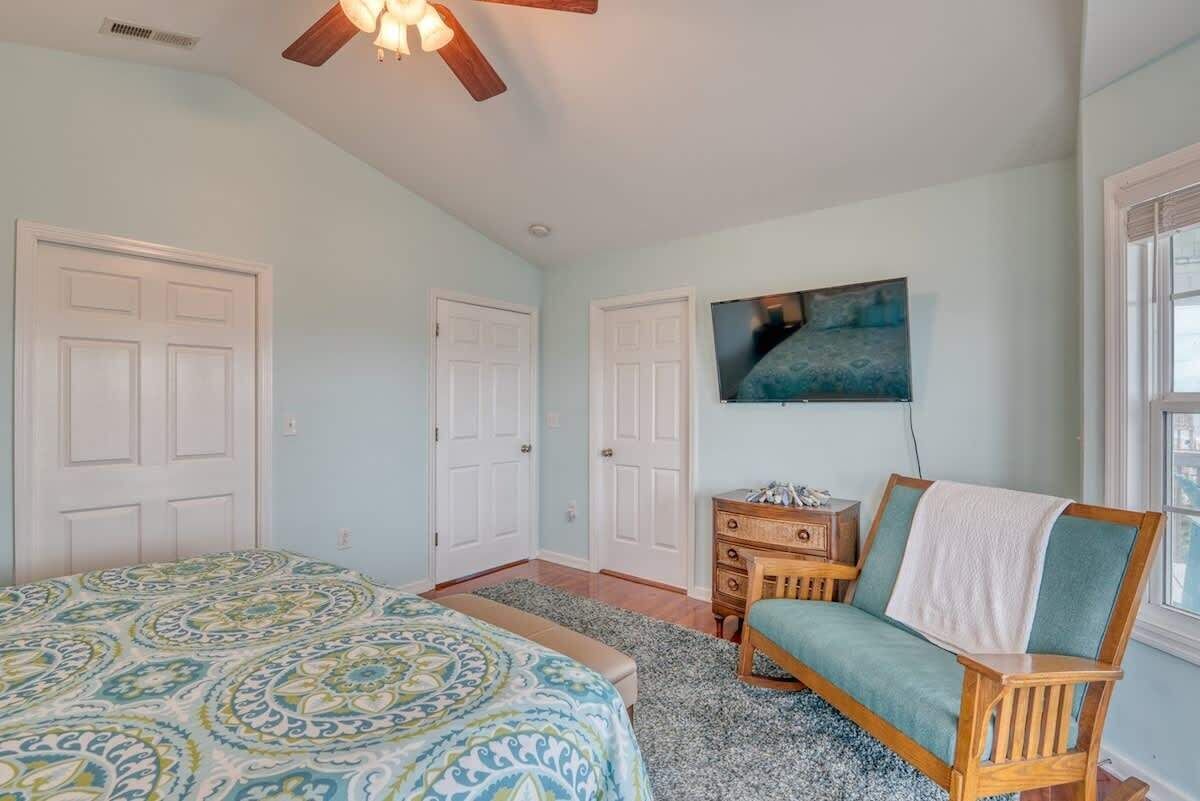 A bedroom with a bed, a wooden chair, a dresser, and a painting on the wall.