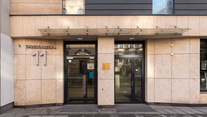 Une entrée d’immeuble au design moderne, avec une porte en verre, une plaque portant le numéro « 11 » et un panneau.