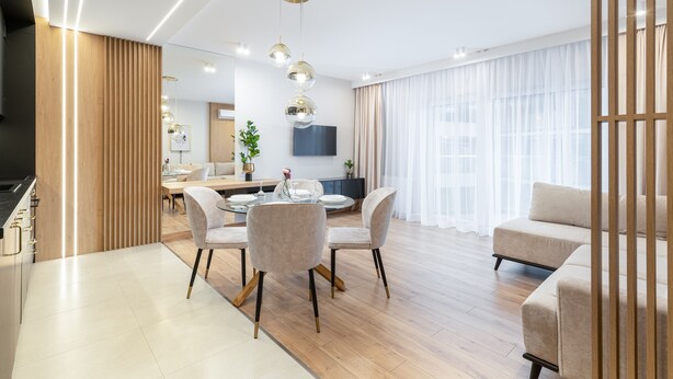 Un salon moderne comprenant un coin repas, un parquet et une grande fenêtre agrémentée de rideaux légers.