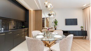 Un espace repas moderne avec une table en verre, des chaises blanches et un lustre.